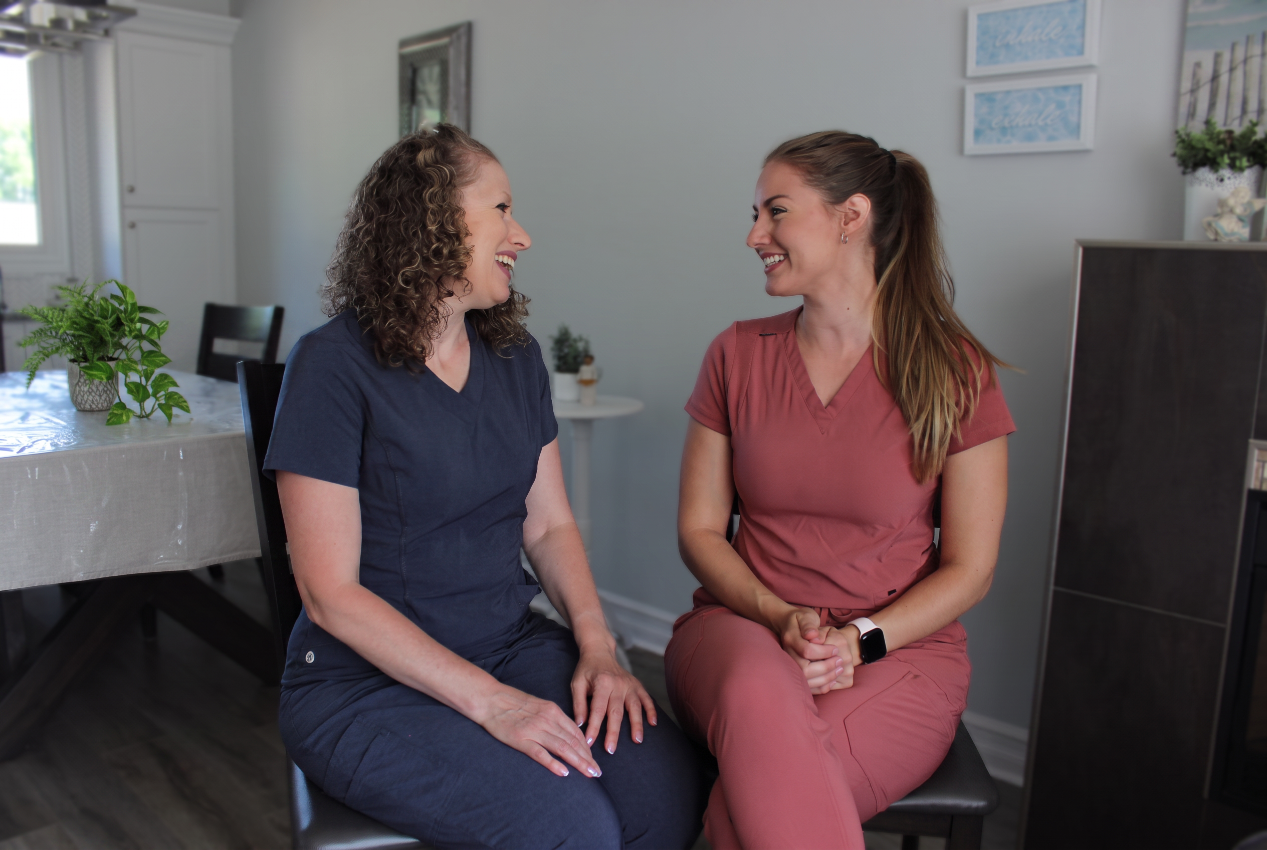 Two YolanCare nurses in scrubs sharing a warm conversation